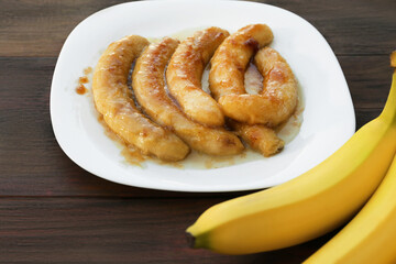 Delicious fried and fresh bananas on wooden table, closeup