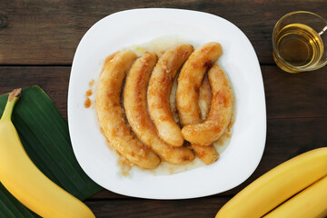 Delicious fried bananas and oil on wooden table, flat lay