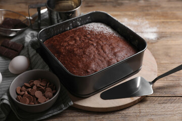 Homemade chocolate sponge cake and ingredients on wooden table