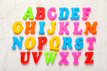 Colorful magnetic letters on white textured background, flat lay. Alphabetical order