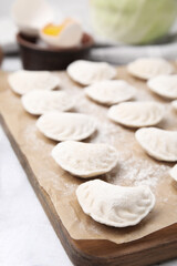 Fototapeta na wymiar Raw dumplings (varenyky) with tasty filling on white wooden table, closeup