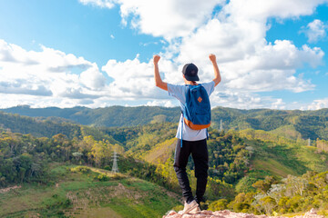 Man standing and celebrating after reaching the top of the mountain and contemplating the beautiful view of the mountains. Walking outdoors in nature. Concept of success and overcoming difficulties.
