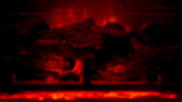 Defocused warm fireplace burning in dark room.