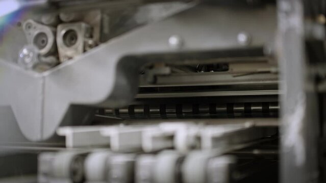 Close up of a printing machine, paper moving on the production line, traveling on the right.
