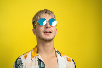 Carefree young man in bright motley shirt dyed blond mirrored round glasses teashades. Guy optimist...