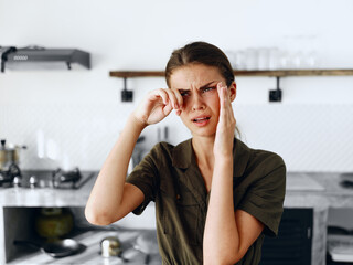 Portrait of a sad tired woman with a sore head in the kitchen, domestic problems, unstable emotional state, onion tears