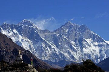 In Tengboche, Nepal, an awe-inspiring sight unfolds as the towering giants of Mt. Everest and Mt. Lhotse dwarf a diminutive stupa in their magnificent shadow..