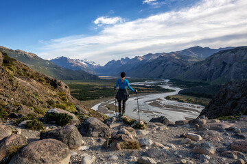 female hiker on the top of mountain looking at a valley