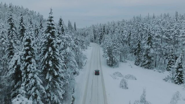 Electric vehicle driving in beautiful snowy landscape in Norway with snow covered tree tops