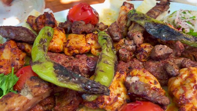 Traditional Turkish big meat platter mixed grill with vegetables and fresh pide ekmek bread in Bodrum Turkey, authentic tasty food, 4K shot