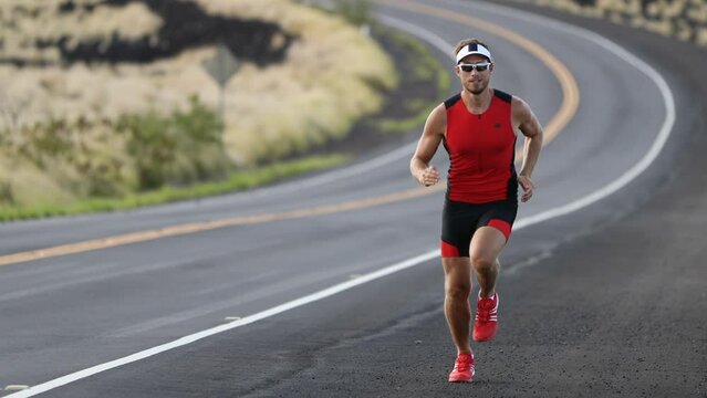Triathlete running in triathlon suit training for ironman. Male runner exercising running uphill on road Kailua-Kona, Big Island, Hawaii. SLOW MOTION