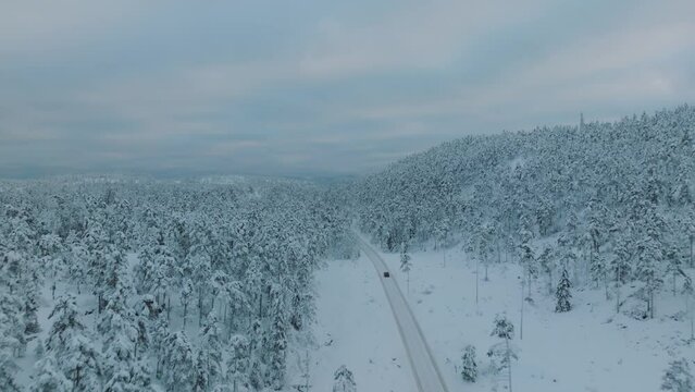 Drone shot chasing an EV driving in beautiful big snowy landscape in Norway.
