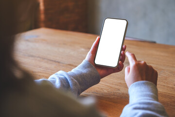 Mockup image of a woman holding and touching on mobile phone with blank desktop screen in cafe