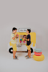 Two boys  playing and having fun in front of  ice cream truck stand