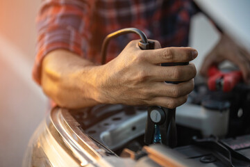 Man holding red and black battery cable for charging the car. Car Repair and maintenance concept