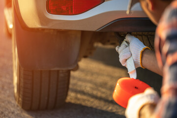 Man holding emergency car towing line and hook on backside of car on the roadside. Car accident,...