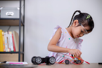 Asian students learn at home by coding robot cars and electronic board cables in STEM, STEAM, mathematics engineering science technology computer code in robotics for kids' concepts.