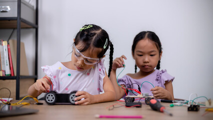 Asian students learn at home by coding robot cars and electronic board cables in STEM, STEAM, mathematics engineering science technology computer code in robotics for kids' concepts.