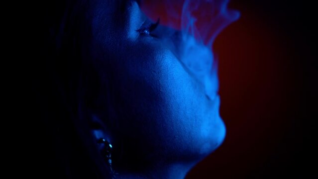 Close up shot of smoking and enjoying smoke in studio lighting by blue light
