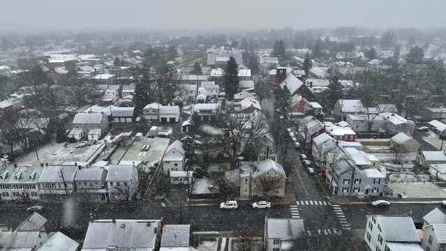 Downtown in small American town during snowfall. Active snowstorm with flakes and flurries flying through shot. Beautiful white snow covered housing and neighborhood.