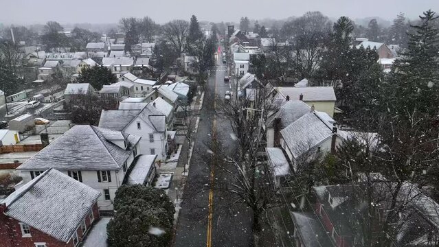 Snow storm over American small town. Aerial drone shot of houses and building accumulating snow on winter day in Pennsylvania.