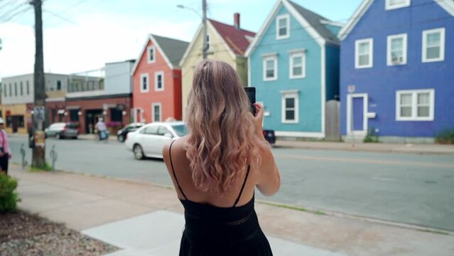Woman taking photo of colourful buildings on her cell phone in Halifax, Nova Scotia, Canada