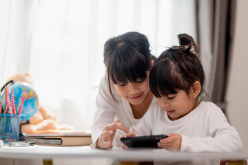 Concept kids and gadgets. Two little girls siblings sisters look at the phone and smile. They hold a smartphone watch videos, learn, play games, speak online. Internet for children. Parental control