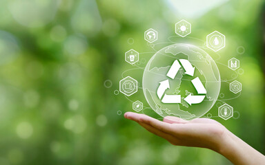 hand holding the earth on a green background with icon recycle in the concept of reuse reduce...
