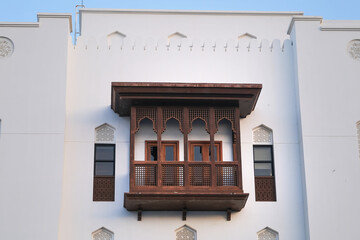 Carved brown wooden balcony with ornament on a white building wall