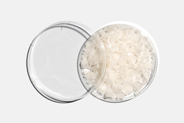 Flake salt in Petri dish with plastic lid on white laboratory table. Chemical ingredient for Cosmetics and Toiletries product. Top View