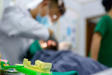 Focus prints yellow dentures. Dentist making dentures Blurred background, dentist treating patient...