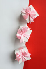 Three gift boxes with pink satin ribbon on white and red background.