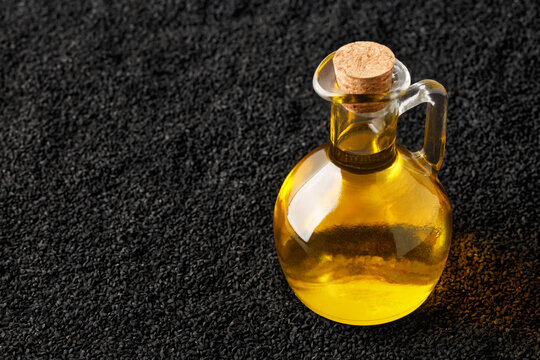 black cumin oil in bottle and scattered seeds as background