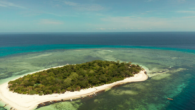 Tropical island in the blue sea with coral reef, top view. Small island with sandy beach. Summer and travel vacation concept, Mantigue island, Philippines, Mindanao