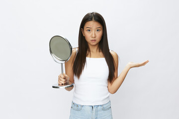 Asian woman with mirror in hand facial skin problems, acne and inflammation, red rash and...