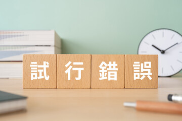 試行錯誤と書かれたブロックが置かれたデスク
