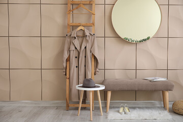 Stylish interior of modern hall with bench, wooden ladder with clothes and mirror