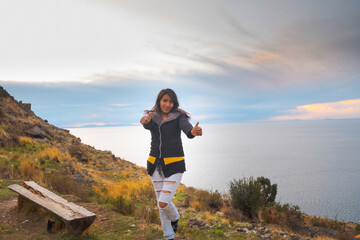 latin woman happy and smiling at sunset on the shores of lake titicaca