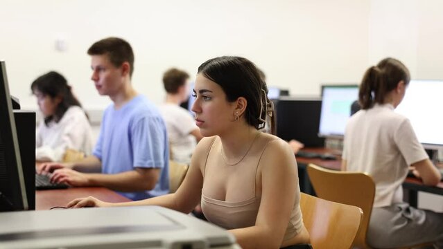 Smart Latin female teenager learning computer science while she is using a PC in the computer classroom
