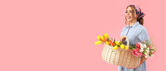 Beautiful happy young woman with basket of flowers on pink background with space for text