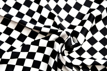 Blurred defocused black and white square and rhombus fabric pattern. Fabric with folds
