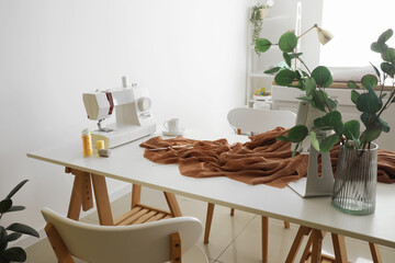 Tailor's workplace with sewing machine and cloth in light atelier