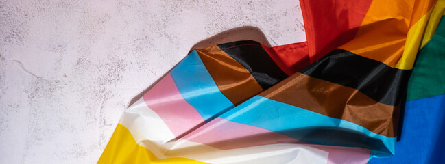 Banner Rainbow LGBTQIA flag made from silk material on concrete background with copy space for your...