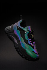 Stylish sneaker with neon gradient on black background. Glowing creative fashion shoe