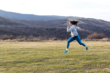 Jogger woman run in nature far away from urban city and exercise at the end of day in the middle of field