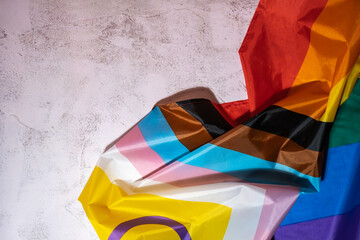 Rainbow LGBTQIA flag made from silk material on concrete background with copy space for your text....