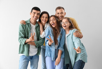 Fototapeta premium Group of happy friends showing victory gesture on light background