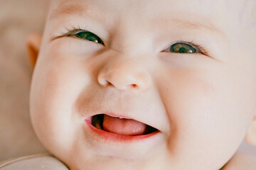 Close-up portrait of a happy baby. The plump face of a newborn with a blissful smile. Sweet smile...