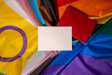 Empty paper blank on Rainbow LGBTQIA flag made from silk material. Mock up template copy space for...