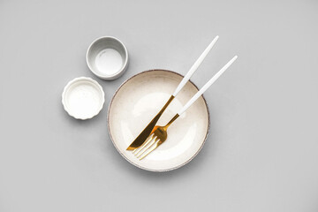 Table setting with golden cutlery on grey background